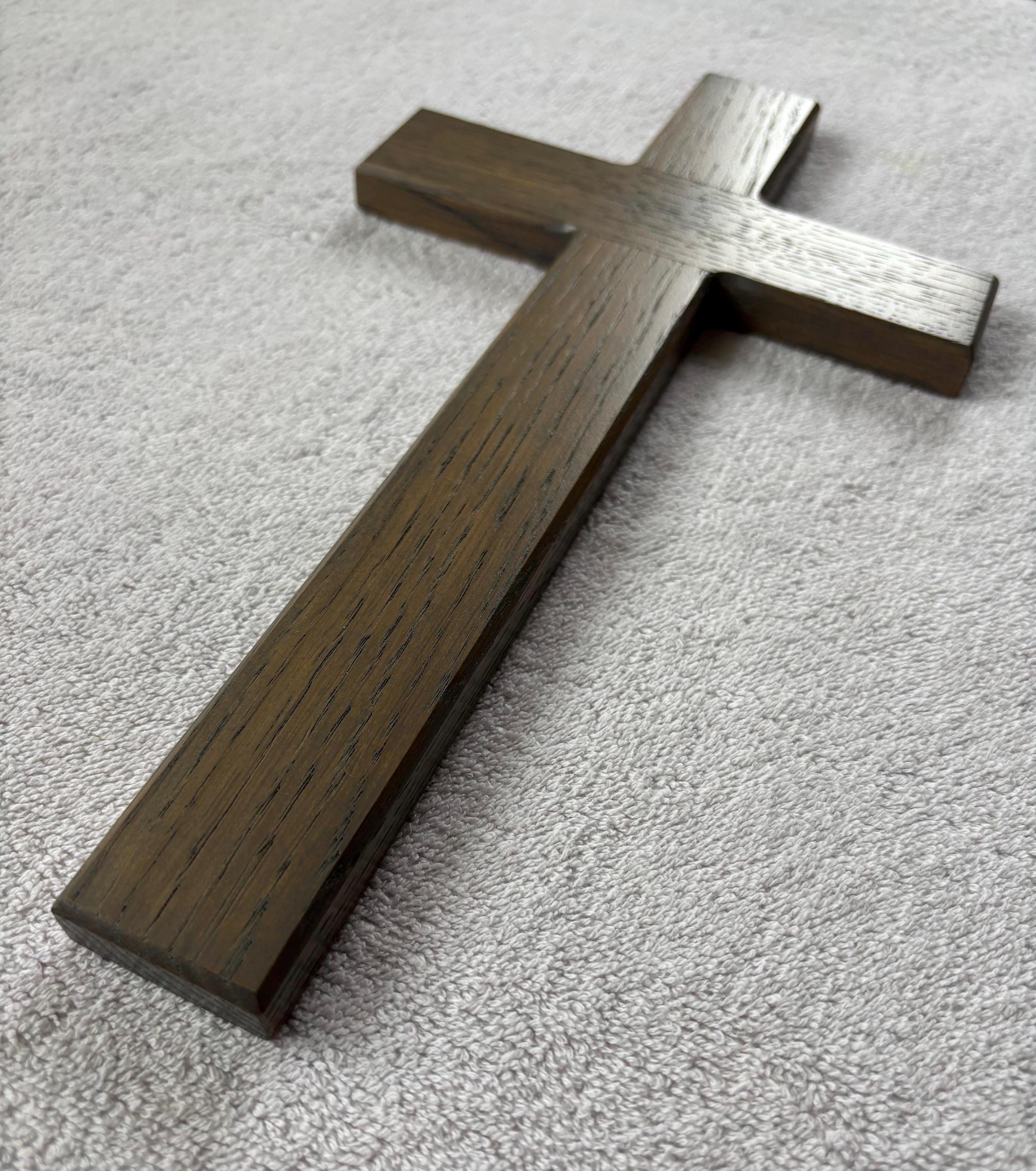 May include: A dark brown wooden cross with a smooth surface and visible wood grain.